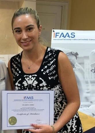 Dr. Marisol Gomez holding her certificate from the International Fellowship in Advanced Aesthetic Science (IFAAS).